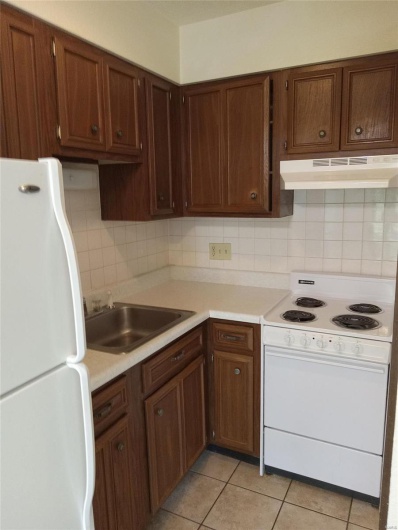 Kitchen featuring decorative backsplash, light tile patterned floors, white appliances, and sink