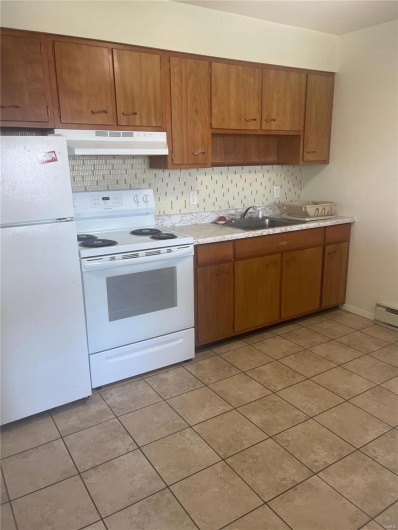 Kitchen with light tile patterned flooring, white appliances, sink, and tasteful backsplash