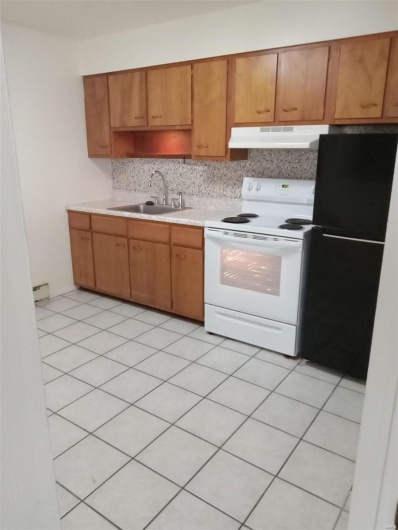Kitchen featuring electric range, sink, black fridge, decorative backsplash, and light tile patterned floors