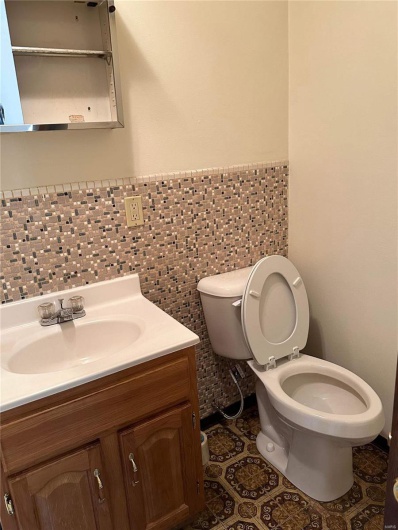 Bathroom featuring tile patterned flooring, vanity, toilet, and tile walls