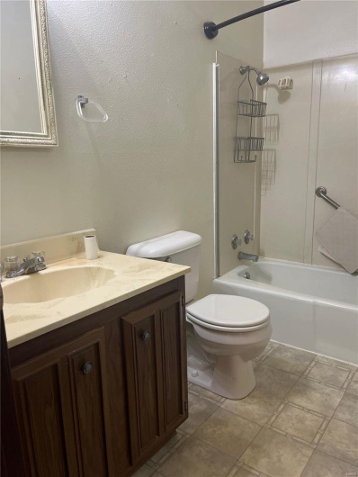 Full bathroom featuring tile patterned flooring, vanity, tiled shower / bath combo, and toilet