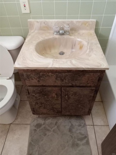 Bathroom with tile patterned floors, vanity, toilet, and tile walls