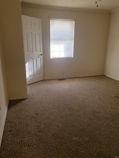 Carpeted empty room featuring ceiling fan and a textured ceiling