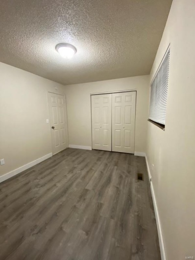 Unfurnished bedroom with dark hardwood / wood-style flooring, a closet, and a textured ceiling