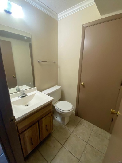 Bathroom featuring toilet, tile patterned flooring, vanity, and ornamental molding