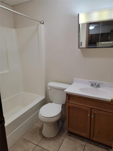 Full bathroom with tile patterned floors, vanity, tub / shower combination, and toilet