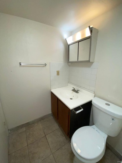 Bathroom featuring tile patterned flooring, vanity, tasteful backsplash, and toilet