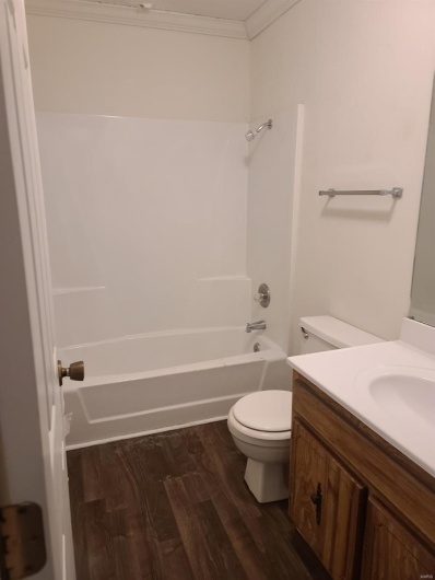 Full bathroom featuring  shower combination, toilet, hardwood / wood-style flooring, vanity, and ornamental molding
