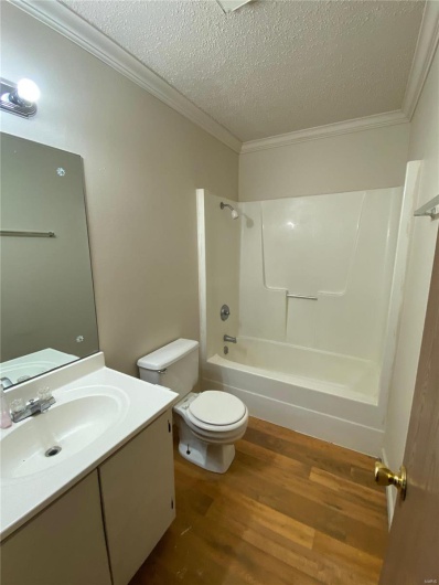 Full bathroom featuring crown molding, wood-type flooring, a textured ceiling, shower / tub combination, and vanity