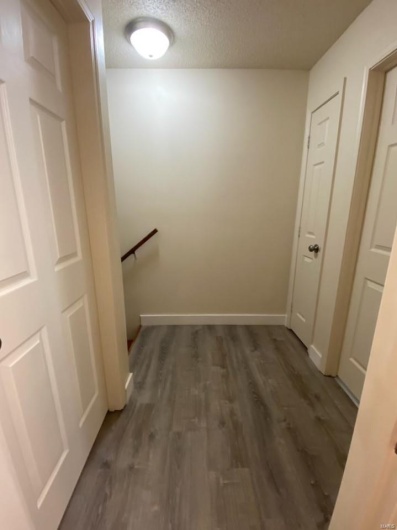 Hall with a textured ceiling and dark wood-type flooring