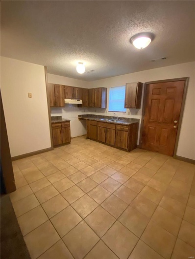 Kitchen featuring light tile patterned flooring, sink, and a textured ceiling