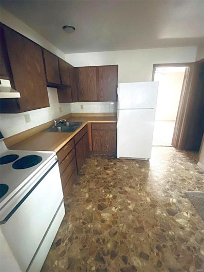 Kitchen with sink, tasteful backsplash, ventilation hood, white appliances, and dark brown cabinets