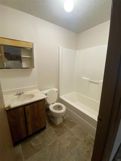 Full bathroom featuring vanity, bathtub / shower combination, tile patterned floors, toilet, and a textured ceiling