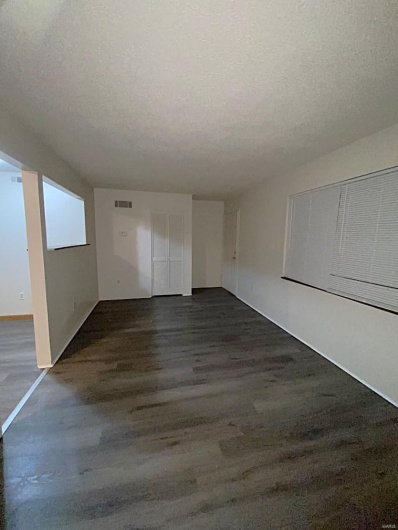 Empty room with a textured ceiling and dark wood-type flooring