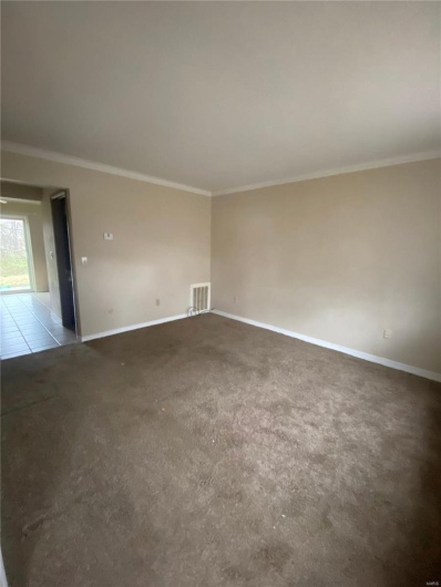 Carpeted empty room featuring ornamental molding