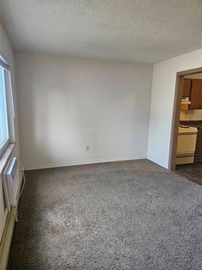 Carpeted spare room with an AC wall unit and a textured ceiling