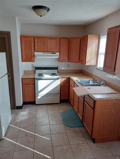 Kitchen with white appliances, tasteful backsplash, and light tile patterned flooring