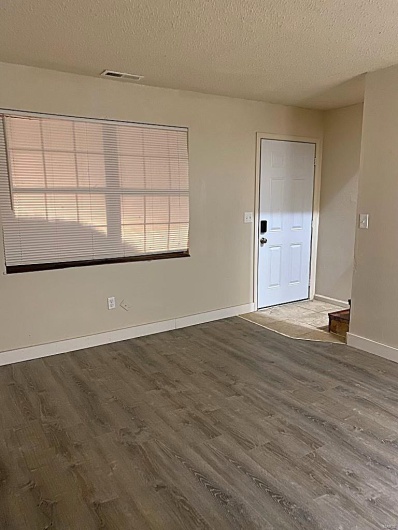 Unfurnished room featuring wood-type flooring, a textured ceiling, and a healthy amount of sunlight