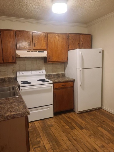 Kitchen with a textured ceiling, white appliances, and dark wood-type flooring