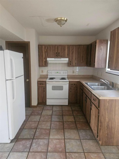 Kitchen with decorative backsplash, white appliances, and sink