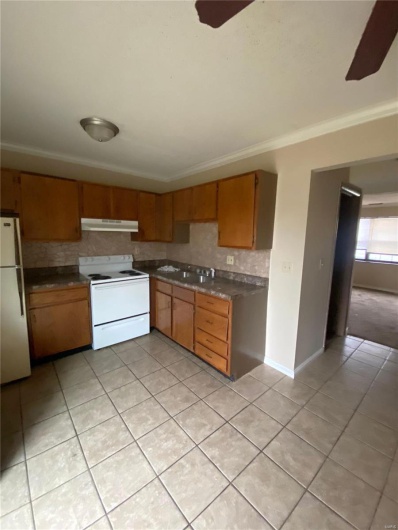 Kitchen with white appliances, ceiling fan, ornamental molding, and backsplash