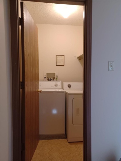 Clothes washing area featuring independent washer and dryer and a textured ceiling