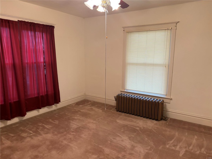 Unfurnished room featuring carpet flooring, radiator heating unit, and ceiling fan