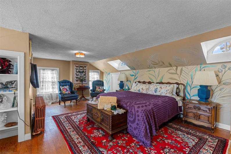 Bedroom featuring lofted ceiling with skylight, hardwood / wood-style floors, and a textured ceiling