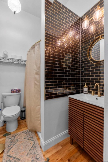 Bathroom featuring toilet, backsplash, vanity, and wood-type flooring
