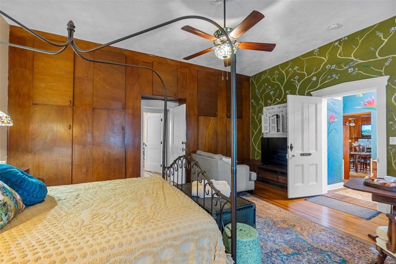 Bedroom with wooden walls, hardwood / wood-style floors, and ceiling fan