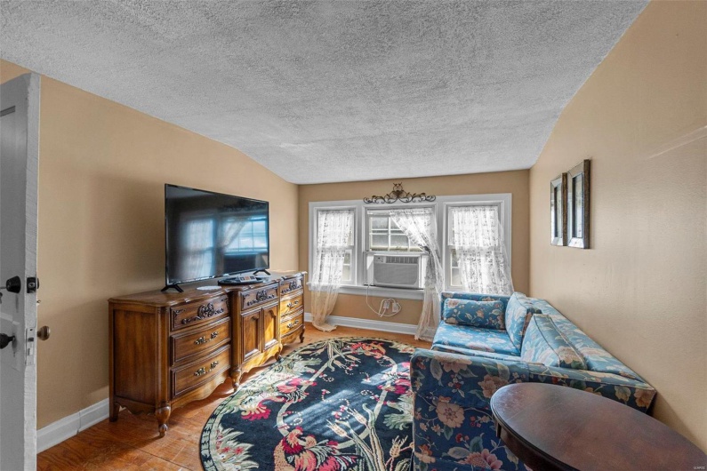 Living room with hardwood / wood-style flooring, a textured ceiling, cooling unit, and lofted ceiling