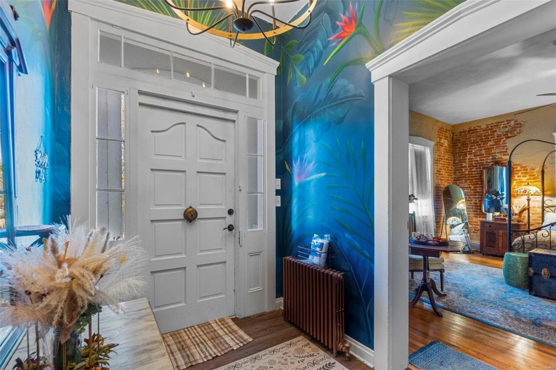 Foyer featuring an inviting chandelier, radiator heating unit, wood-type flooring, and brick wall