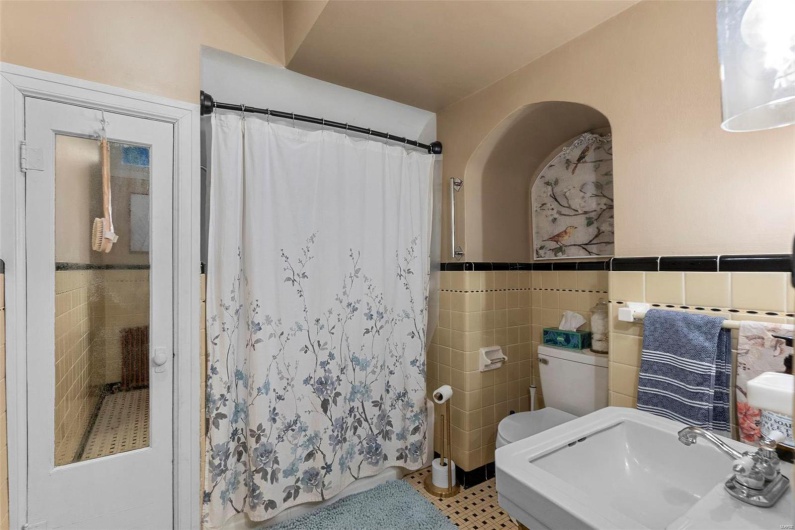 Bathroom with tile walls, sink, toilet, and a shower with curtain
