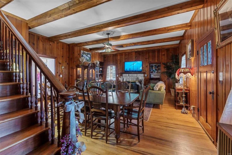 Dining area featuring hardwood / wood-style floors, ceiling fan, wooden walls, and beam ceiling