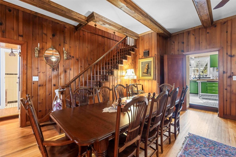 Dining area featuring beamed ceiling, wooden walls, and light wood-type flooring