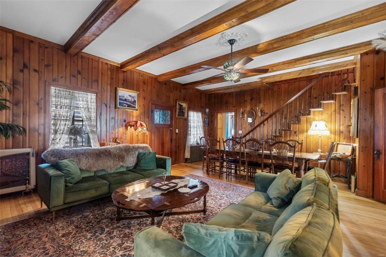 Living room with light hardwood / wood-style flooring, wooden walls, and beam ceiling