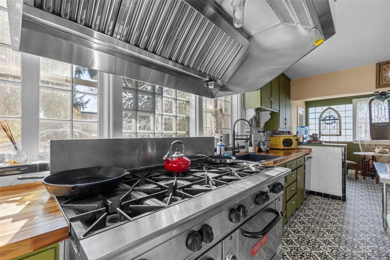 Kitchen featuring butcher block counters, sink, green cabinets, and wood-type flooring