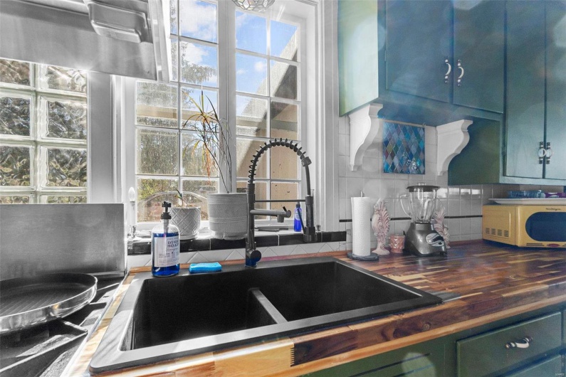 Kitchen with decorative backsplash, a healthy amount of sunlight, sink, and wood counters