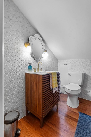Bathroom with toilet, vanity, lofted ceiling, and hardwood / wood-style floors