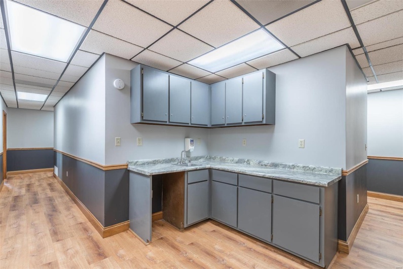 Kitchen with gray cabinetry, a paneled ceiling, light hardwood / wood-style flooring, and sink