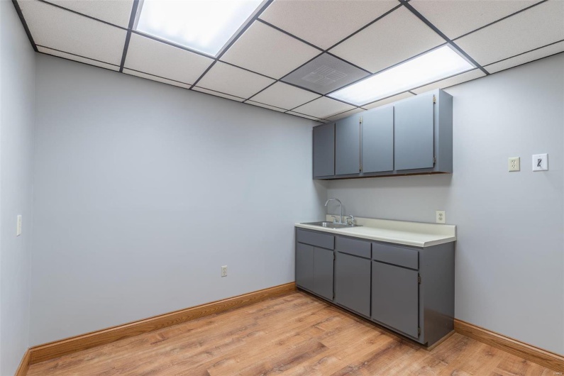 Kitchen with gray cabinetry, sink, a drop ceiling, and light wood-type flooring