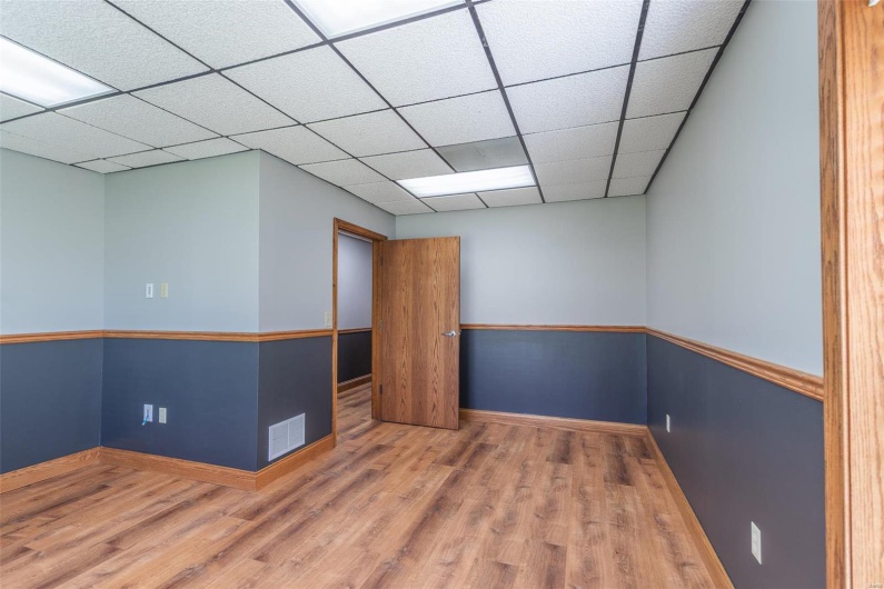 Empty room with hardwood / wood-style floors and a drop ceiling
