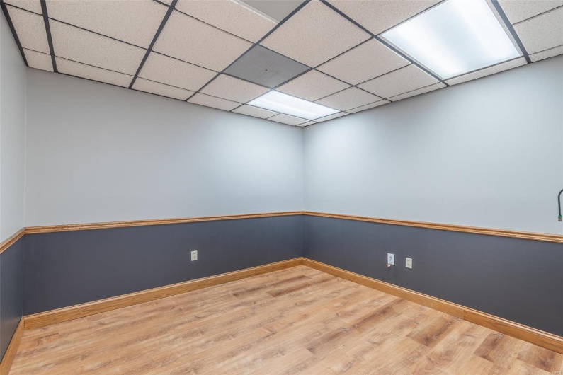 Empty room with wood-type flooring and a drop ceiling