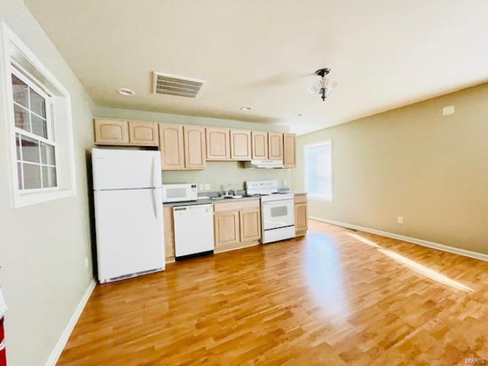 Kitchen featuring light wood-type flooring, white appliances, sink, and light brown cabinetry