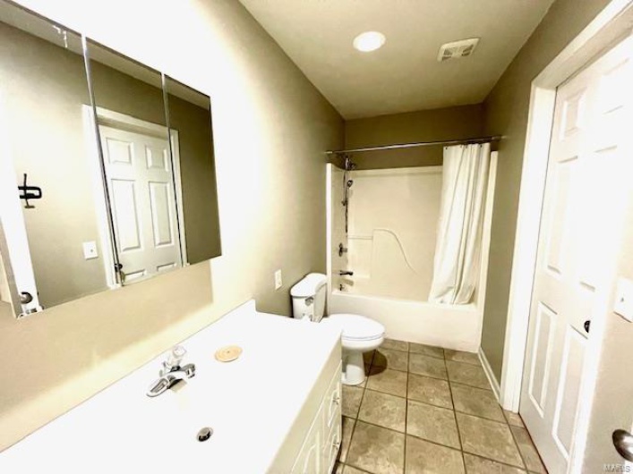Full bathroom featuring shower / bath combination with curtain, vanity, toilet, and tile patterned floors