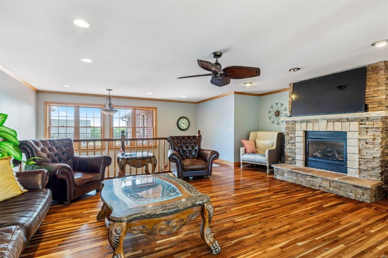 Living room with a fireplace, ceiling fan, hardwood / wood-style floors, and ornamental molding