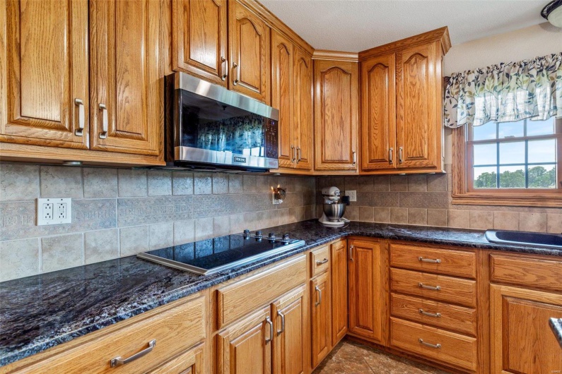 Kitchen with stovetop, backsplash, and dark stone counters