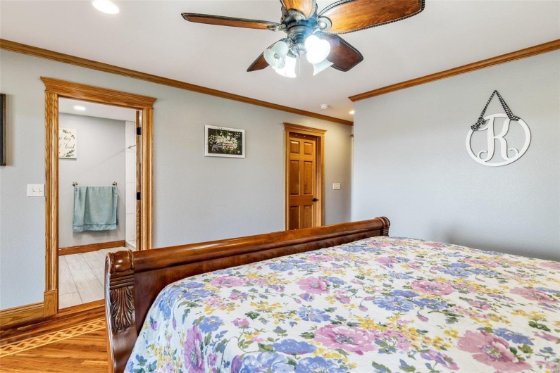 Bedroom with ceiling fan, light hardwood / wood-style floors, and ornamental molding