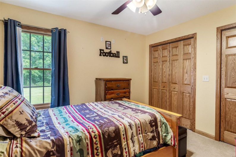 Bedroom with ceiling fan, a closet, light colored carpet, and multiple windows