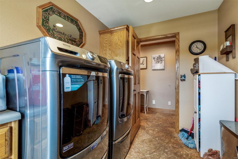 Washroom featuring separate washer and dryer, light tile patterned floors, and cabinets